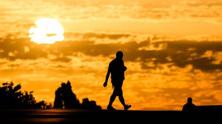 Ein Mann geht bei Sonnenaufgang über eine Straße.