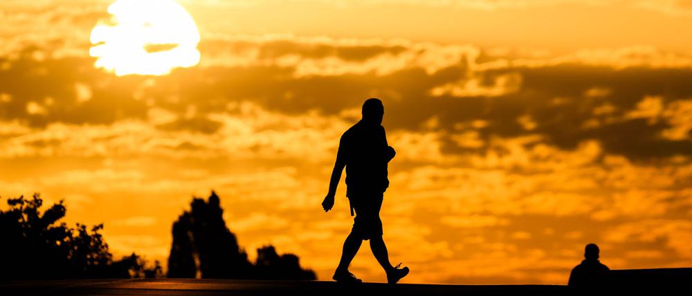 Ein Mann geht bei Sonnenaufgang über eine Straße.