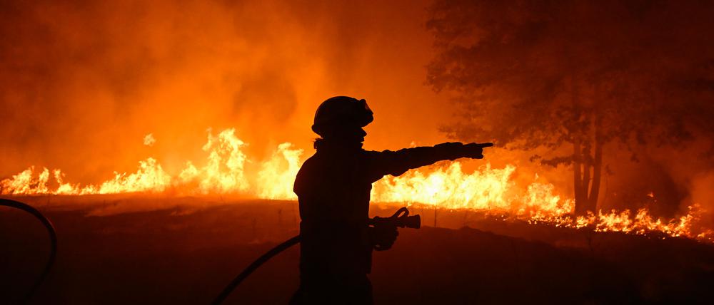 TOPSHOT - A firefighter works to extinguish a wildfire in the village of Vilaza, near Verin, Ourense province, northwestern Spain, on August 12, 2025. A man died from burns and thousands of people were forced to evacuate as wildfires swept through parts of Spain, fueled by strong winds and a searing heat wave that has gripped the country for 10 days. (Photo by MIGUEL RIOPA / AFP)