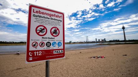 Ein Hinweisschild am Paradiesstand in Düsseldorf weist auf die Gefahren beim Schwimmen im Rhein hin.