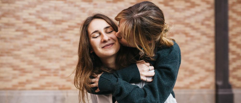 Zwei Frauen umarmen und küssen sich.