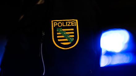 Ein Polizist steht neben einem Polizeiauto. (Archiv)
