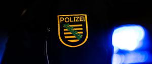 Ein Polizist steht neben einem Polizeiauto. (Archiv)
