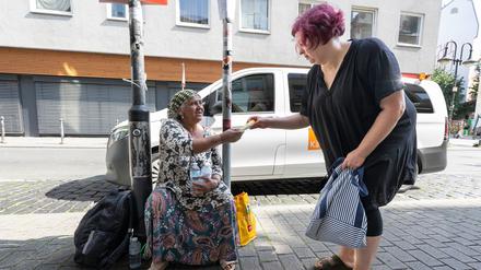 Sozialarbeiterin Eliane Reuter (r) überreicht einer obdachlosen Frau aus Rumänien Sonnencreme.