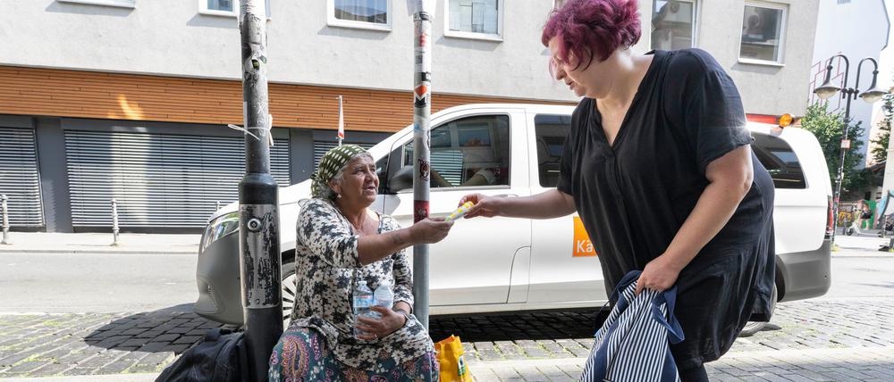 Sozialarbeiterin Eliane Reuter (r) überreicht einer obdachlosen Frau aus Rumänien Sonnencreme.