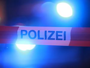 Blaulichter leuchten hinter einem Absperrband der Polizei. (Symbolbild) 
