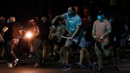 Regierungsanhänger werfen Leuchtraketen auf regierungskritische Demonstranten, als es am 14. August 2025 in Belgrad zu Zusammenstößen kommt.