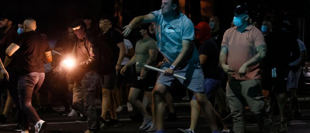 Regierungsanhänger werfen Leuchtraketen auf regierungskritische Demonstranten, als es am 14. August 2025 in Belgrad zu Zusammenstößen kommt.