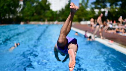 Ein Mann springt im Sommerbad Kreuzberg ins Becken. 