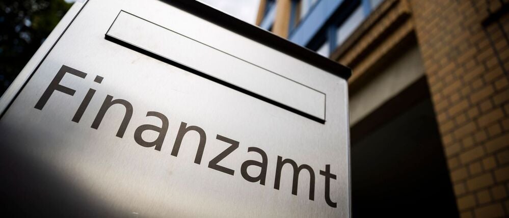 Ein Briefkasten des Finanzamtes steht vor einem Gebäude.