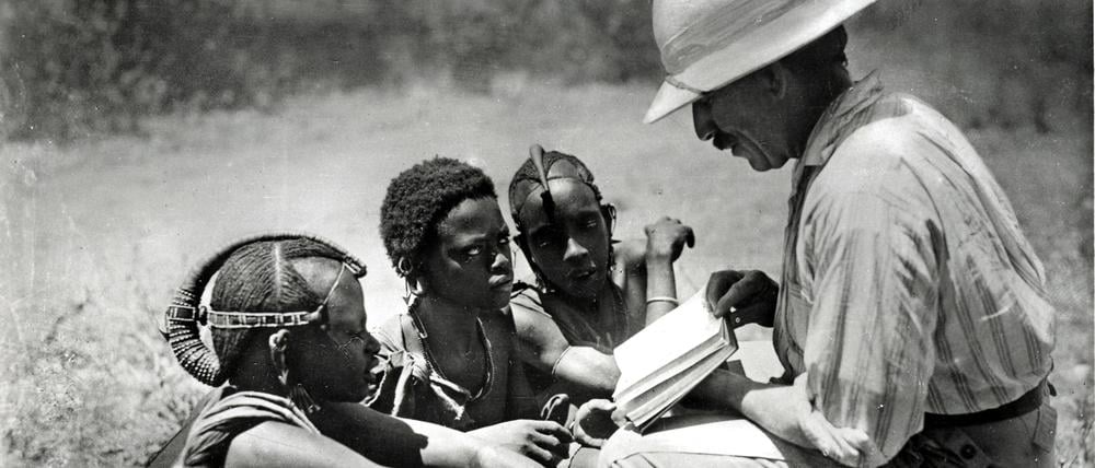 Ein deutscher Kolonialist bringt Kindern in Afrika das Lesen bei. Auf eigene kulturelle Traditionen wurde keine Rücksicht genommen, die Kolonialherren wähnten sich überlegen.
