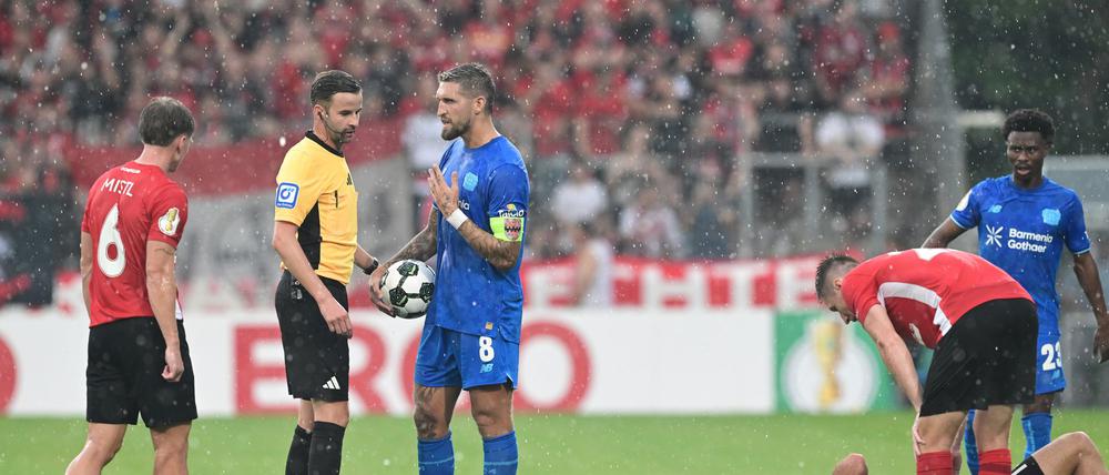Schiedsrichter Michael Bacher (2.v.l.) muss das Spiel in Großaspach unterbrechen