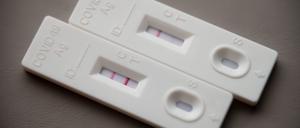 Ein positiver Corona-Schnelltest (l) liegt auf einem Tisch neben einem Corona-Schnelltest, der schwach eine positive Linie hat.