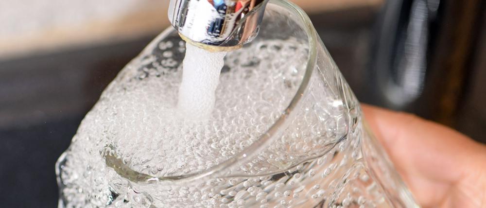 Eine Frau füllt ein Glas mit Trinkwasser aus dem Hahn (Symbolfoto).