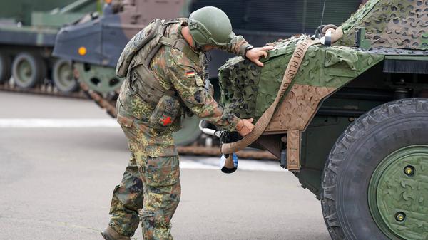 Ein Bundeswehrsoldat überprüft die Tarnung und Ausrüstung eines Spähpanzers Fennek. 