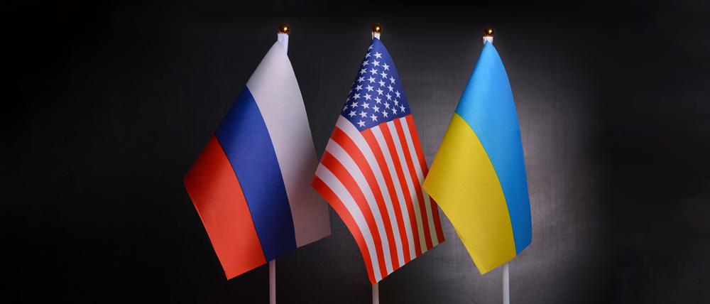 Die Flaggen von Russland, USA und der Ukraine stehen vor schwarzem Hintergrund. Symbolbild für 3er-Gipfel.