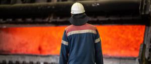 Ein Mitarbeiter der Trimet Aluminium SE steht vor einem Schmelzofen mit heißen flüssigen Aluminium für die Herstellung von speziellen Legierungen. 