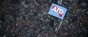 Eine AfD-Parteifahne mit Zahnstocher liegt verdreckt am Boden (Symbolfoto).