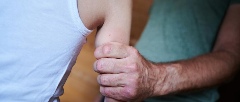 Ein Mann hält ein Kind fest am Arm.