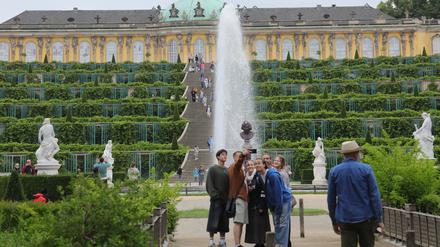 Besucher machen an der großen Treppe vor Schloss Sanssouci ein Selfie.