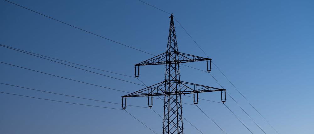 Baden-Württemberg, Rottweil: Ein Strommast ist bei Sonnenaufgang als Silhouette zu sehen.