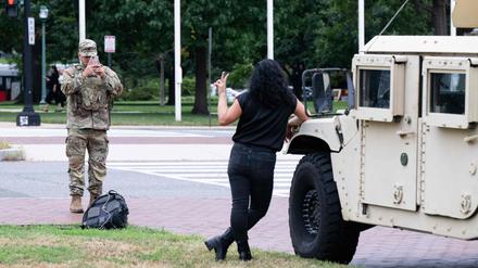 Ein Mitglied der Nationalgarde fotografiert eine Frau vor Militärfahrzeugen nahe der Union Station in Washington. Präsident Donald Trump will nach eigenen Worten gemeinsam mit Soldaten durch die Hauptstadt patrouillieren.