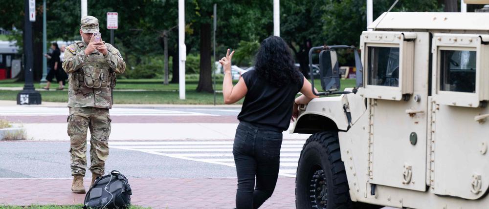 Ein Mitglied der Nationalgarde fotografiert eine Frau vor Militärfahrzeugen nahe der Union Station in Washington. Präsident Donald Trump will nach eigenen Worten gemeinsam mit Soldaten durch die Hauptstadt patrouillieren.
