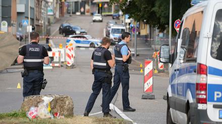 22.08.2025, Saarland, Völklingen: Polizeibeamte untersuchen das Umfeld eines Tatorts.