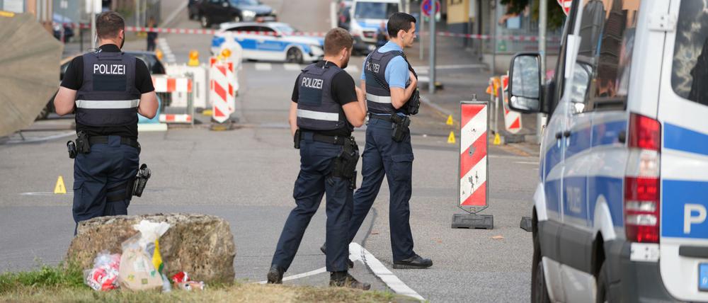 22.08.2025, Saarland, Völklingen: Polizeibeamte untersuchen das Umfeld eines Tatorts.