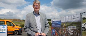 Bundesverkehrsminister Patrick Schnieder (CDU) steht an der Autobahn A1-Lückenanschlussstelle Kelberg an einem Tisch, dessen Platte einst ein Autobahnschild war.