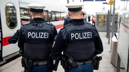 Bundespolizisten stehen vor der Abfahrt eines ICE an einem Gleis im Bahnhof.