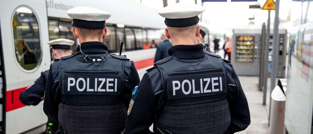 Bundespolizisten stehen vor der Abfahrt eines ICE an einem Gleis im Bahnhof.