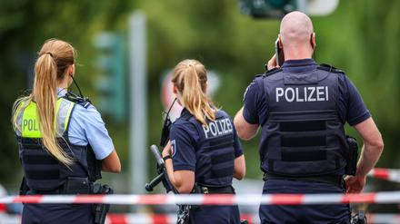 Polizeibeamte stehen zur Absicherung an einer Absperrung am Tatort in Menden.