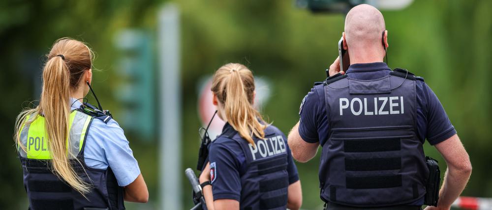 Polizeibeamte stehen zur Absicherung an einer Absperrung am Tatort in Menden.