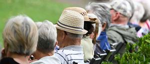Ältere Menschen besuchen in einem Kurpark das Konzert eines Schulorchesters. 