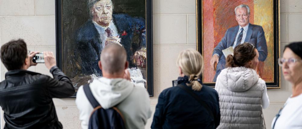 Menschen stehen am Tag der offenen Tür der neuen Bundesregierung im Kanzleramt vor den Porträts der ehemaligen Kanzlern Schmidt (l) und Brandt.