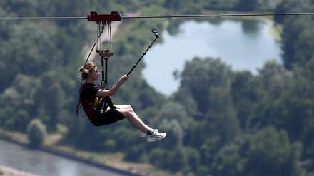 Ein Mädchen fährt in einem Freizeitpark mit einer Zip-Line.