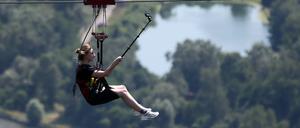 Ein Mädchen fährt in einem Freizeitpark mit einer Zip-Line.