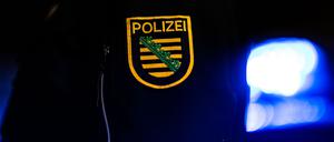 Ein Polizist steht in Dresden neben einem Polizeiauto.