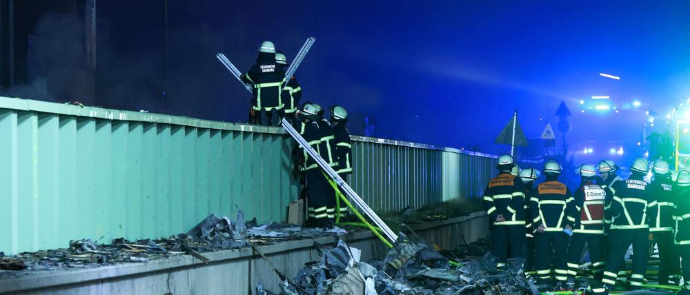 Einsatzkräfte der Feuerwehr sind dabei einen Brand in einem Industriegebiet im Hamburger Hafen zu löschen. Nachdem in einer Lagerhalle in einem Hamburger Gewerbegebiet ein Feuer ausbrach kam es zu mehreren Explosionen.
