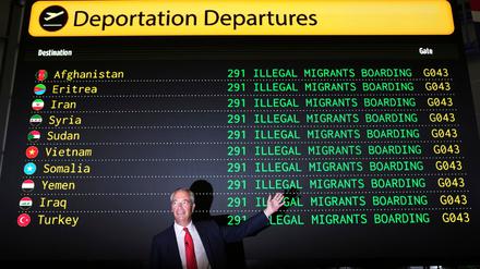 Nigel Farage, posiert während einer Pressekonferenz zur Vorstellung seines Programms «Operation Restoring Justice» im Hangar des Flughafens Oxford vor einer Attrappe der Abflugtafel («Deportation Departures»), auf der verschiedene Länder aufgelistet sind mit dem Hinweis «Illegal Migrants Boarding». 