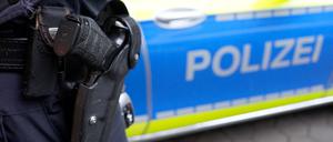 Ein Polizist steht vor einem Einsatzfahrzeug der Polizei.