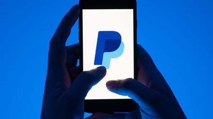 Eine Frau hält ein Smartphone mit dem Logo des Bezahldienst Paypal. (gestellte Szene)