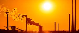 Die Sonne geht in Duisburg hinter Schornsteinen unter. 