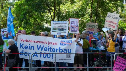Demonstranten protestieren hinter einer Absperrung am Estrel-Hotel unter anderem mit einem Transparent „Kein Weiterbau der A100“ vor Beginn des Festaktes zur Eröffnung des 16. Bauabschnittes der Stadtautobahn A 100 gegen einen Weiterbau der Stadtautobahn. 
