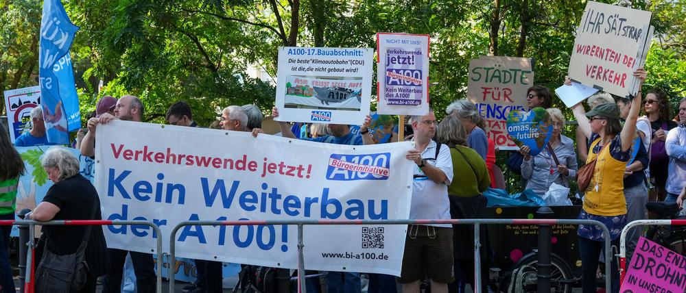Demonstranten protestieren hinter einer Absperrung am Estrel-Hotel unter anderem mit einem Transparent „Kein Weiterbau der A100“ vor Beginn des Festaktes zur Eröffnung des 16. Bauabschnittes der Stadtautobahn A 100 gegen einen Weiterbau der Stadtautobahn.