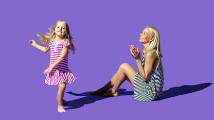 Eine Mutter schaut ihrer tanzenden Tochter zu und klatscht begeistert.