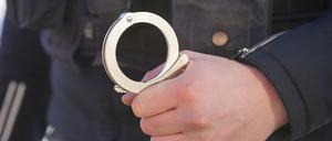 Ein Polizist hält Handschellen in seiner Hand.