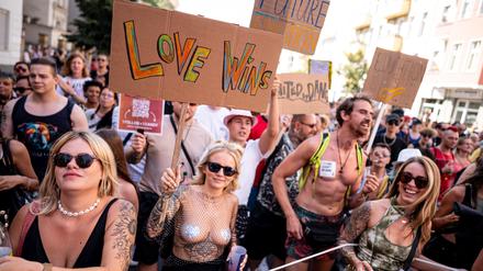 Menschen nehmen im Jahr 2024 an der Technoparade „Zug der Liebe“ - Demonstration für Toleranz, Vielfalt und Miteinander mit einem Schild mit der Aufschrift „love wins“ teil.