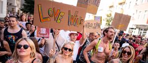 Menschen nehmen im Jahr 2024 an der Technoparade „Zug der Liebe“ - Demonstration für Toleranz, Vielfalt und Miteinander mit einem Schild mit der Aufschrift „love wins“ teil.